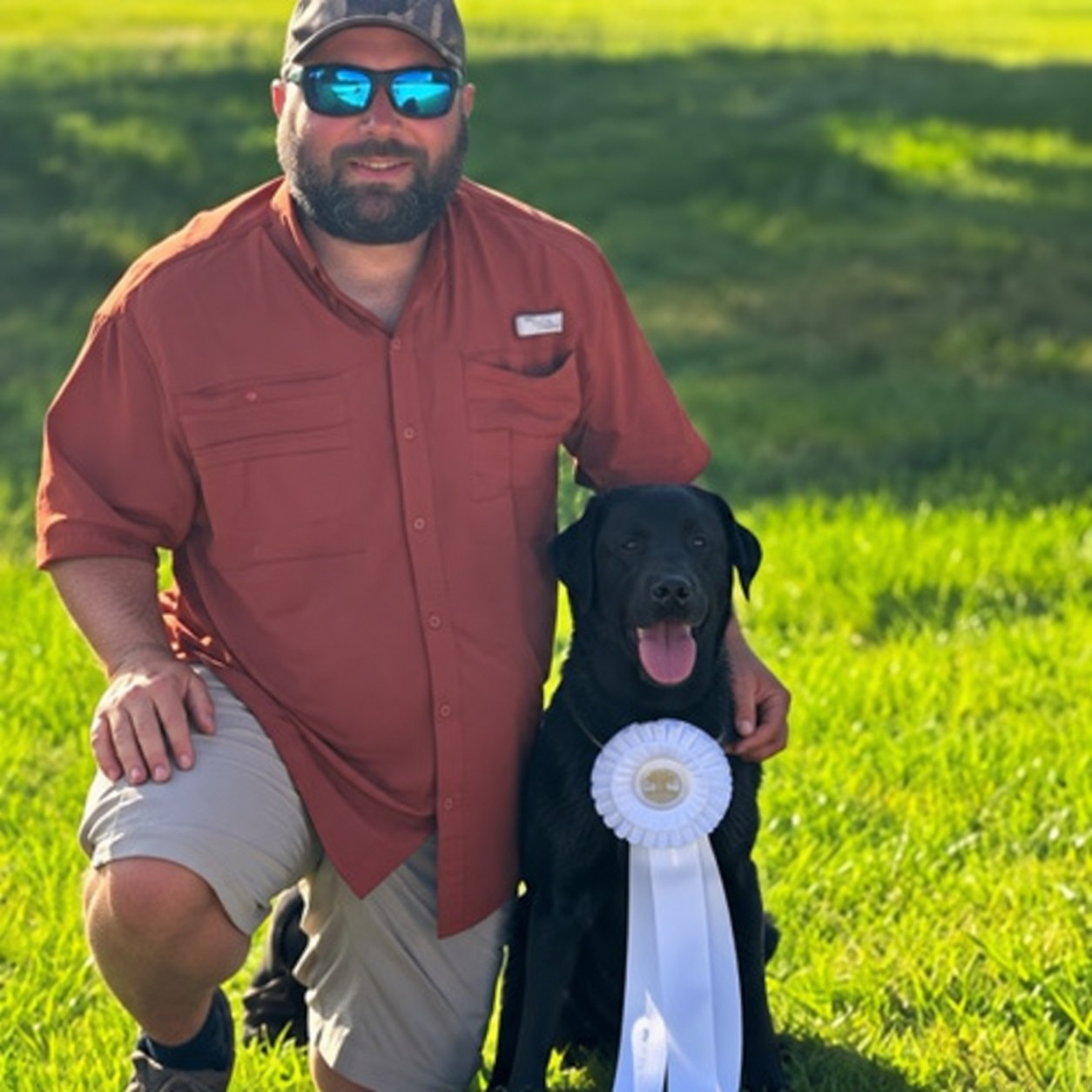 Red River Kennels trainer and black dog with award ribbon